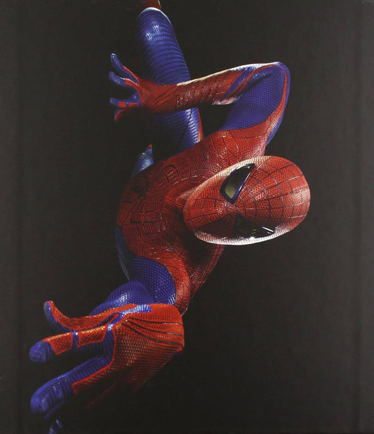 A Spider-Man figure or collectible posed hanging upside down against a dark black background, with the classic red and blue suit and web pattern clearly visible.