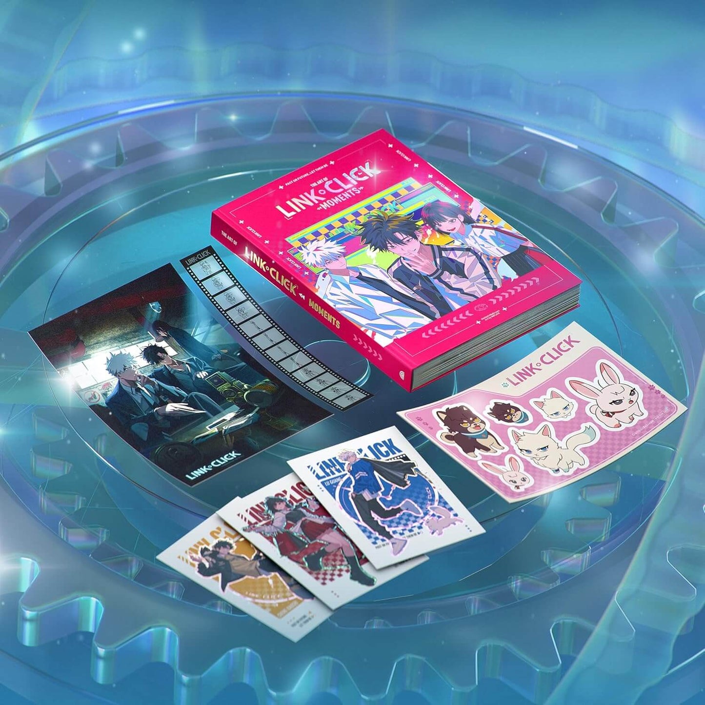 Link:Click! The Movie Collection physical media set displayed on a blue circular platform, including a pink book, a printed card, a sticker sheet, and several small art cards.
