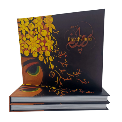 Hardcover "Art of The Breadwinner" book cover standing upright, featuring intricate golden floral headpiece artwork and the film title.