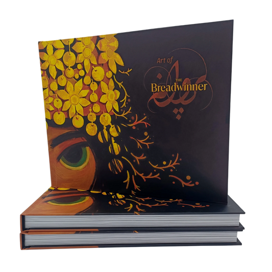 Hardcover "Art of The Breadwinner" book cover standing upright, featuring intricate golden floral headpiece artwork and the film title.