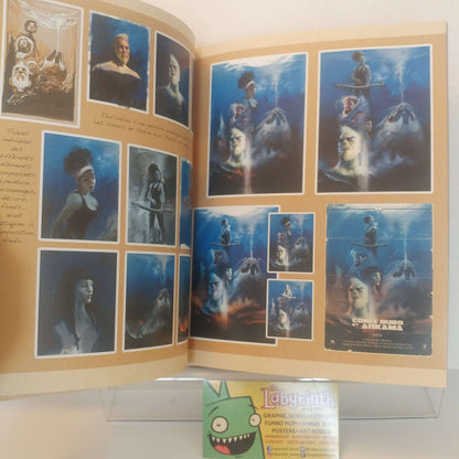An open book or poster display showing multiple printed character art panels, likely from a movie or game poster collection, with a small Labyrinth logo card visible in front on a clear stand.