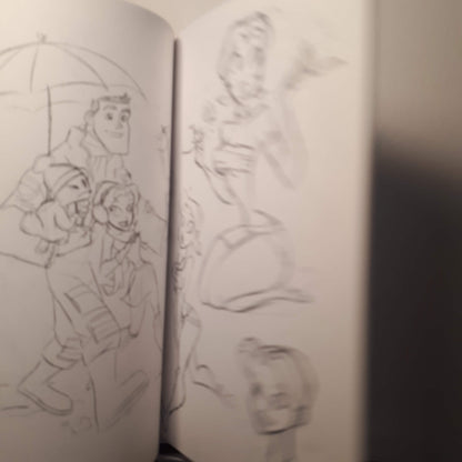 A sketchbook showing pencil drawings of characters, photographed in dim light with the pages slightly blurred.