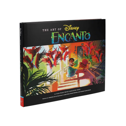 The Art of Disney Encanto hardcover book featuring a black cover with the title in gold and blue-green lettering, and a colorful illustrated scene of the Enchanted Forest on the front.