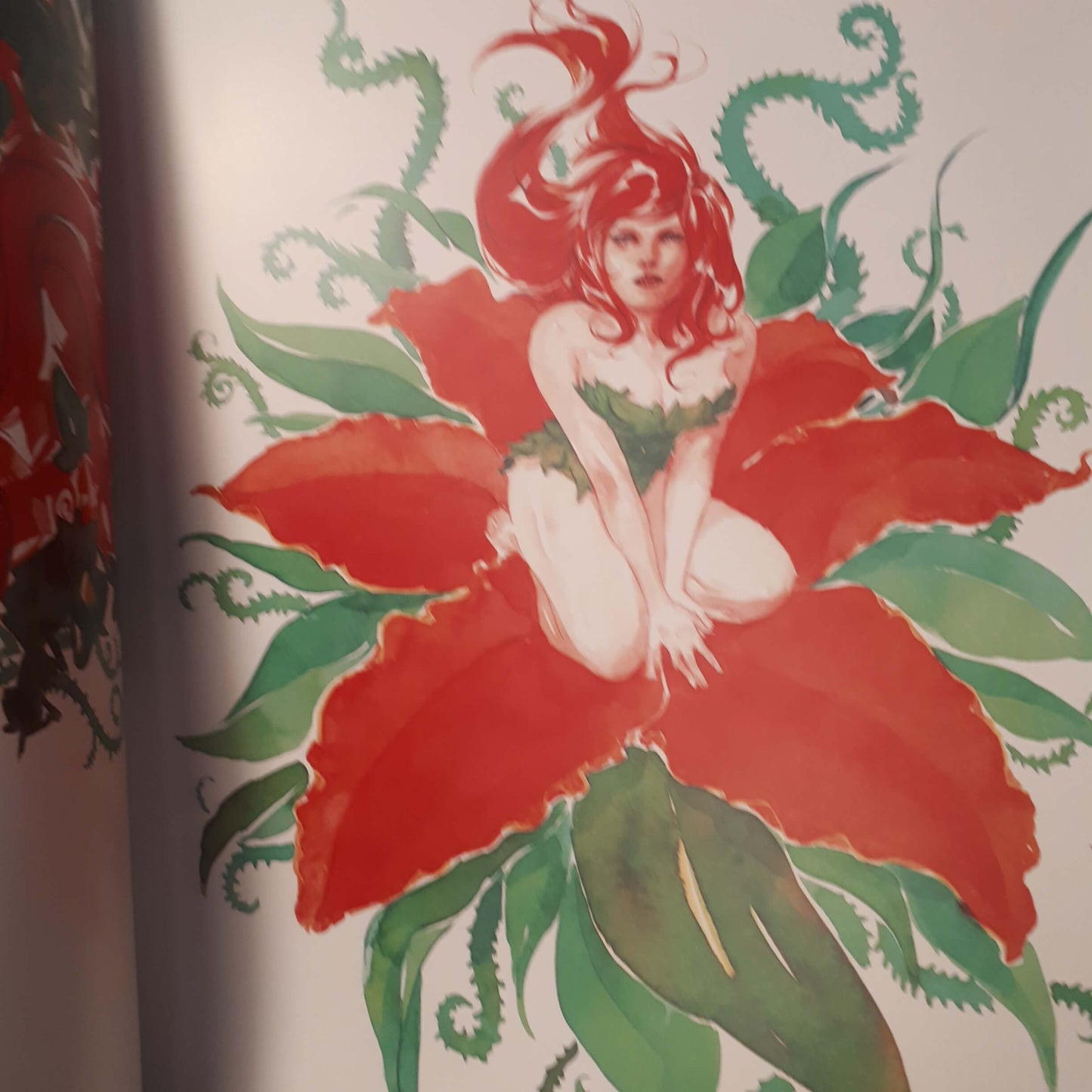 A close-up of a vintage-style illustration printed on a page or book, showing a red-haired woman seated inside a large red flower with green leaves and vine-like details.