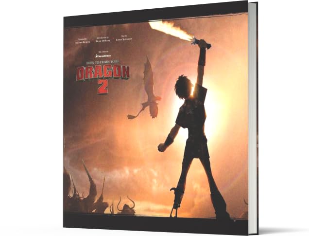 A hardcover book or album cover for 'How to Train Your Dragon 2' shown at an angle against a plain white background. The cover features a dramatic silhouette of a dragon rider holding a flaming sword against a bright orange and yellow sky, with the title 'How to Train Your Dragon 2' and the 'DreamWorks' logo visible.