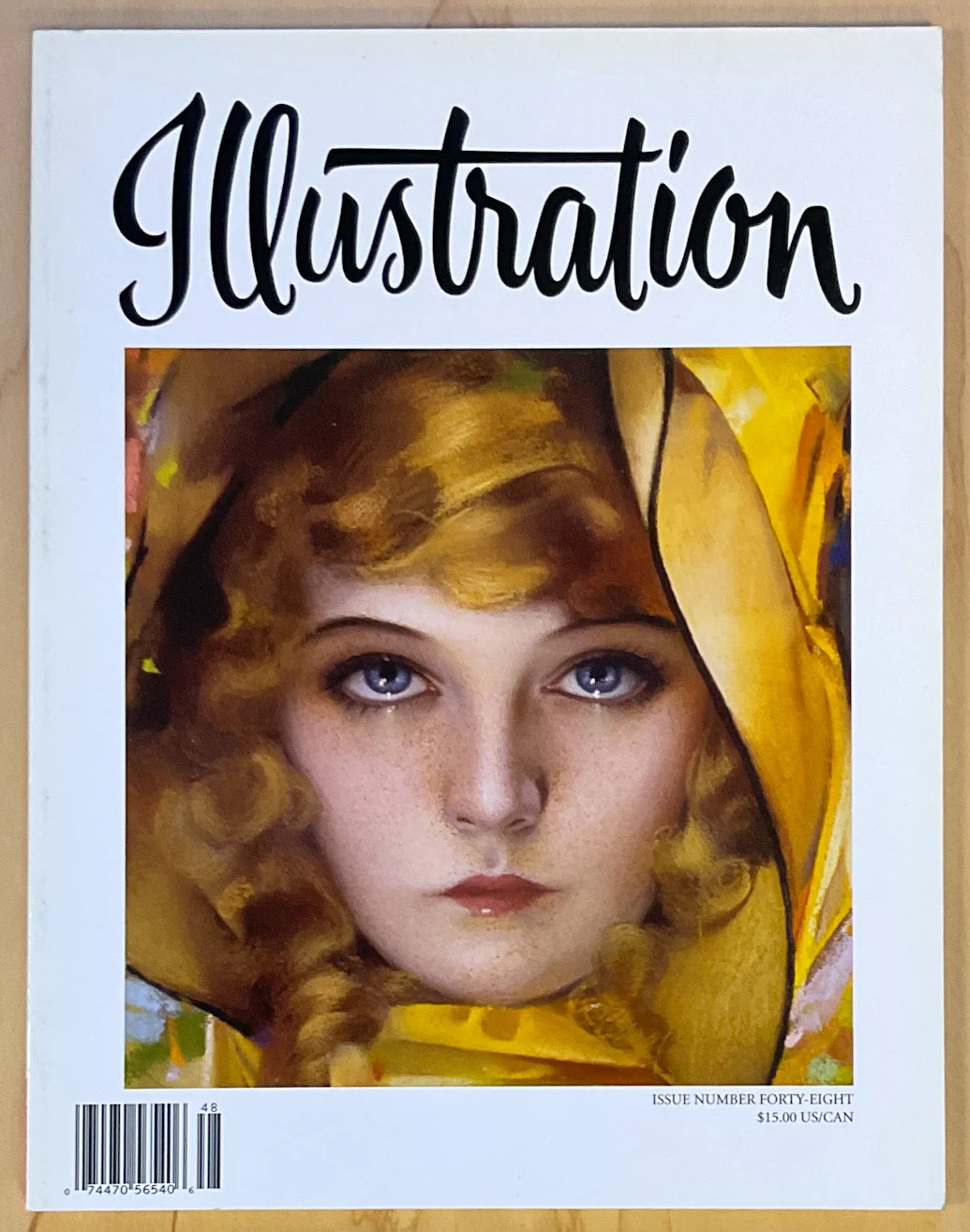 Vintage magazine cover titled 'Illustration' featuring a painted portrait of a woman with curly hair and a yellow head covering, photographed against a light wood background.