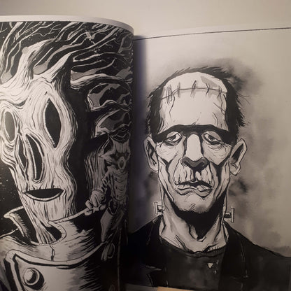 An open art book or magazine showing black-and-white illustrated portraits, with one page featuring a skull-like face and the other showing a stitched horror character.