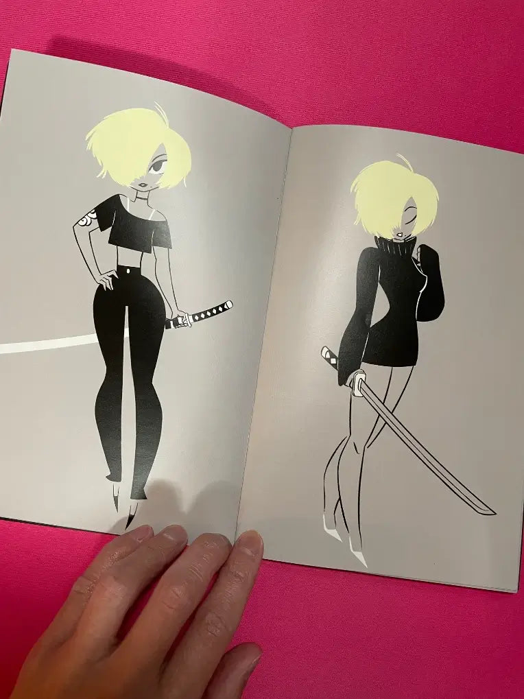 An open art book or magazine showing two stylized illustrations of a blonde woman in black outfits, one fully shaded and one outlined, held by a hand against a bright pink background.