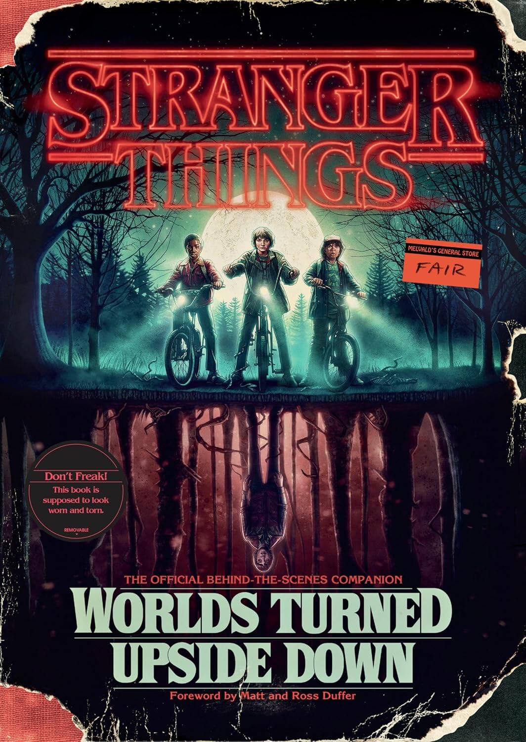 Cover of the book 'Stranger Things: Worlds Turned Upside Down,' featuring three characters from the series with a dark, foreboding atmosphere in a forest setting.