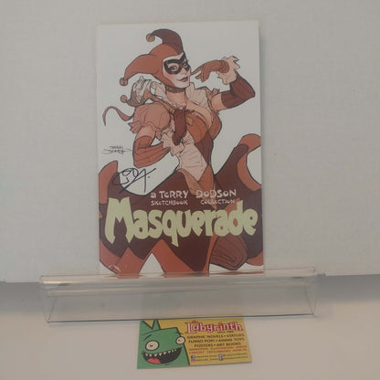 A signed comic book titled 'Masquerade' by Terry Dodson, featuring an illustrated character in a jester costume, displayed on a clear acrylic stand with a Labyrinth card below it.