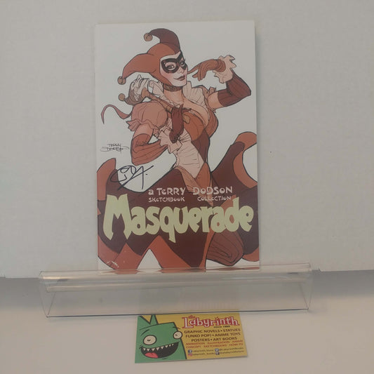 A signed comic book titled 'Masquerade' by Terry Dodson, featuring an illustrated character in a jester costume, displayed on a clear acrylic stand with a Labyrinth card below it.
