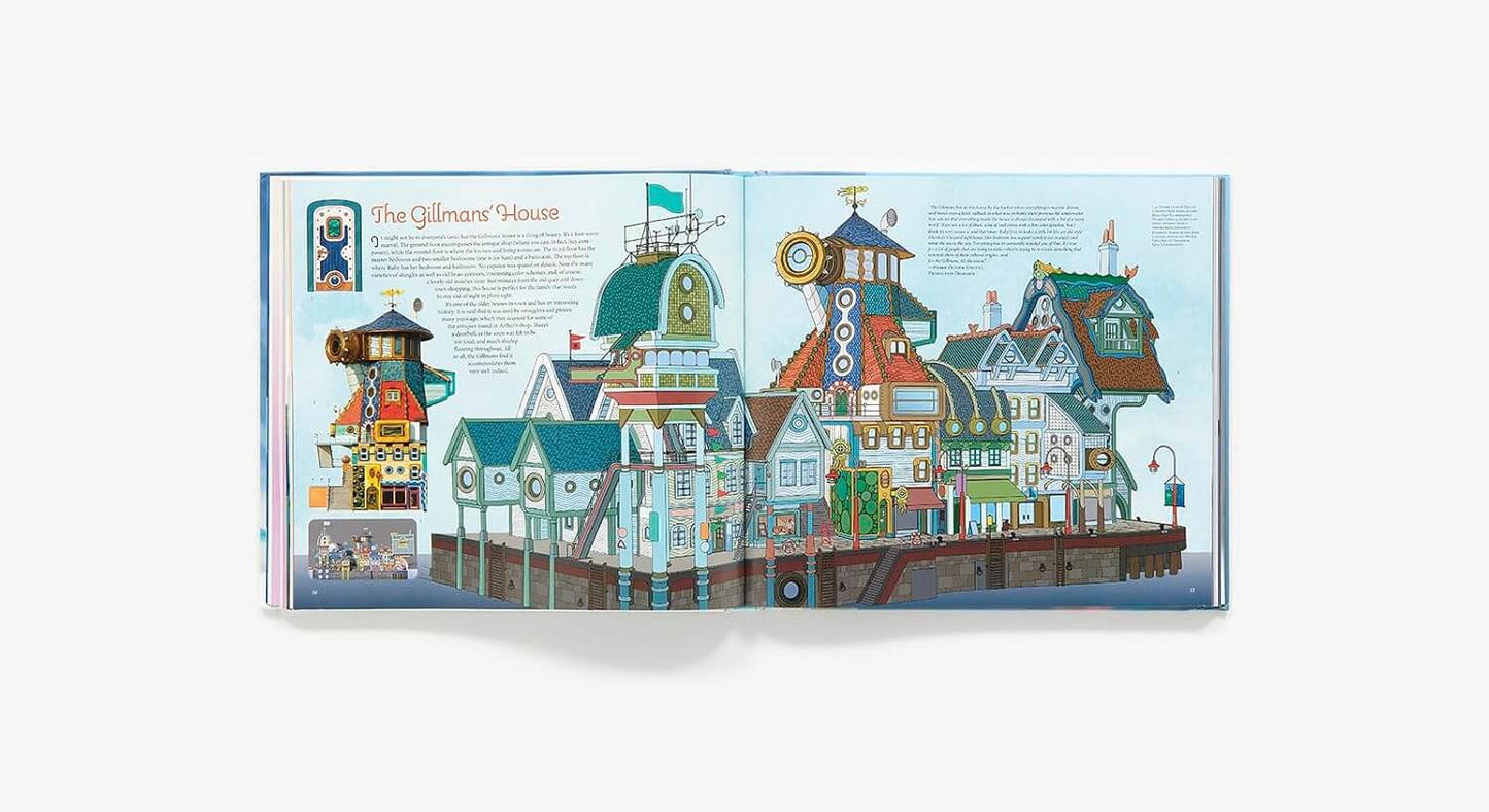 An open illustrated book spread showing colorful seaside houses and a lighthouse under a pale blue sky, photographed against a light gray background.