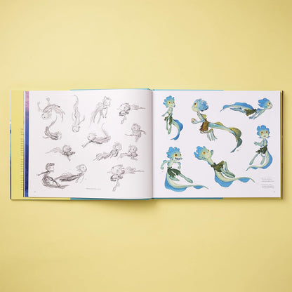 An open art book or concept sketchbook laid flat on a pale yellow background, showing character designs and pencil studies on both pages. The illustrations feature blue, green, and brown fantasy figures on white paper.