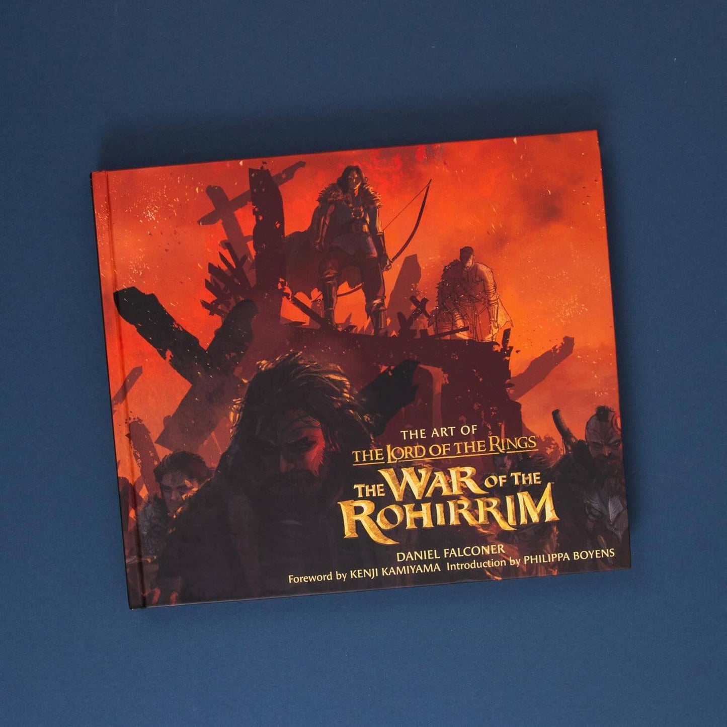 Book titled 'The Art of The Lord of the Rings: The War of the Rohirrim' on a blue background