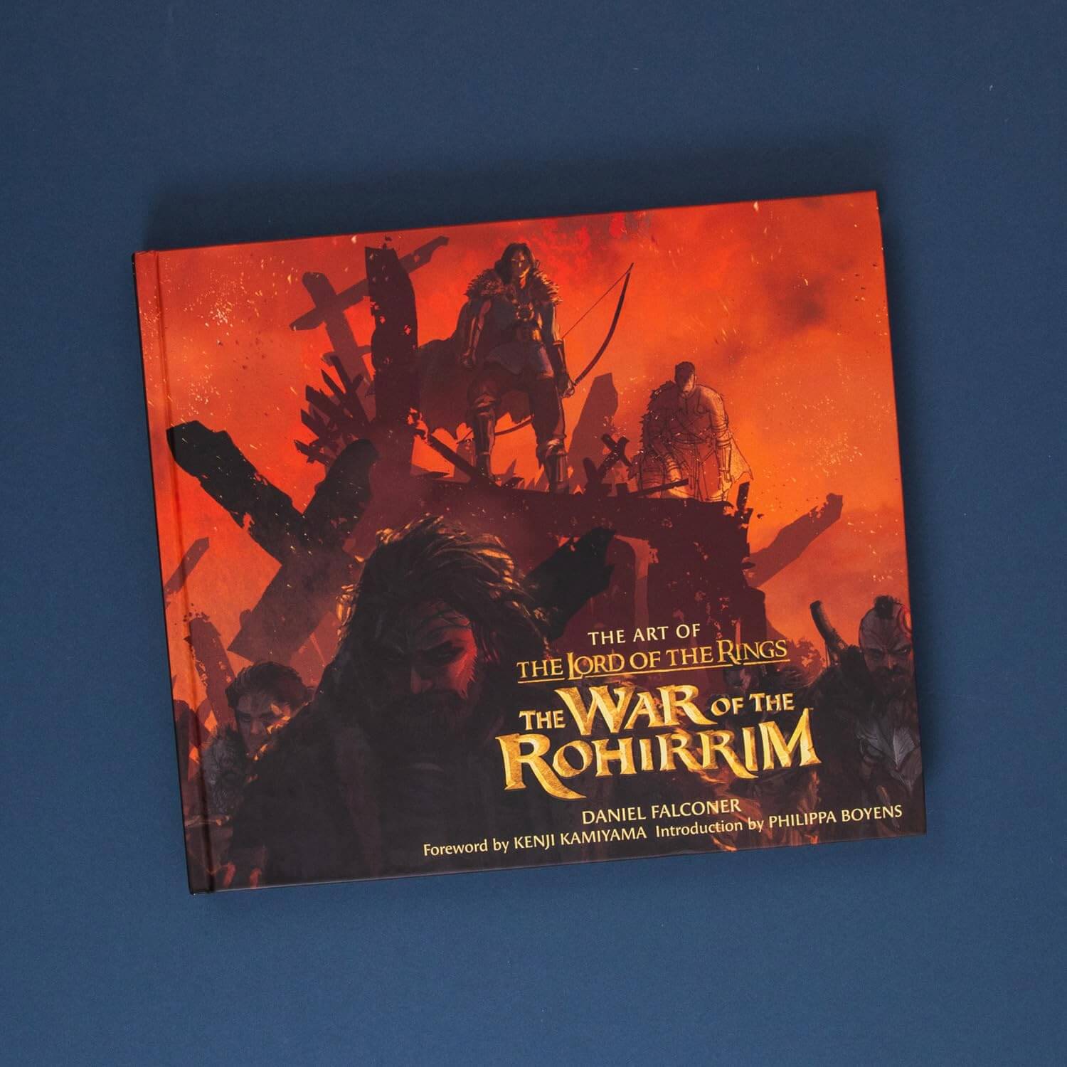 Book titled 'The Art of The Lord of the Rings: The War of the Rohirrim' on a blue background